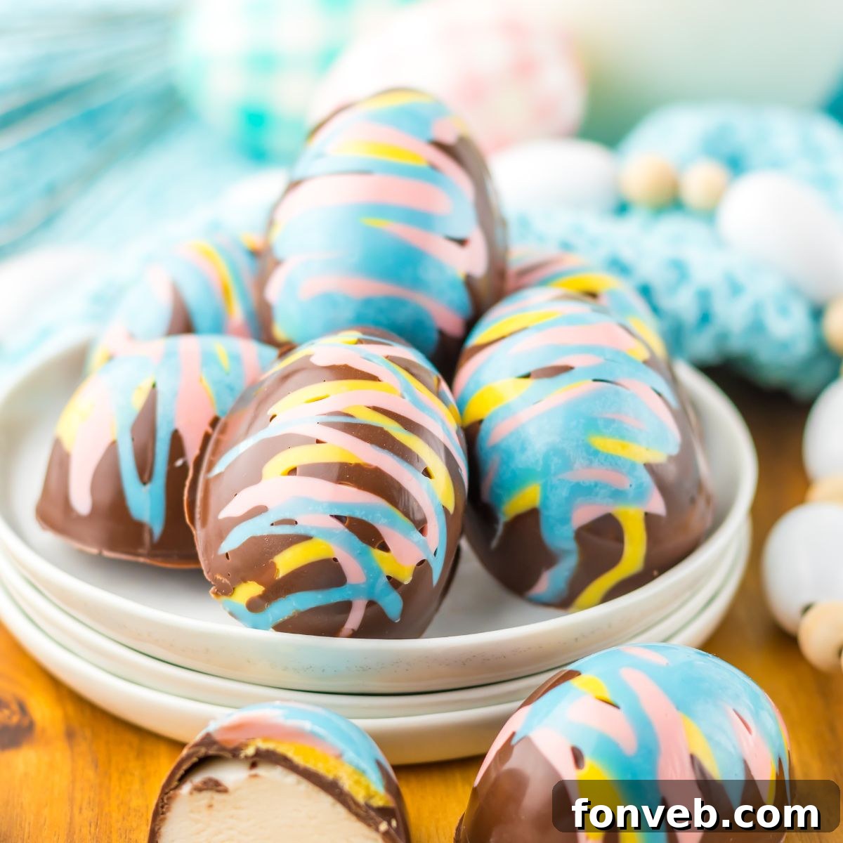 Fluffy Easter Delights 2 Easter Marshmallow Eggs on a plate on table wih an egg slice in half to show the marshmallow filling sitting on table