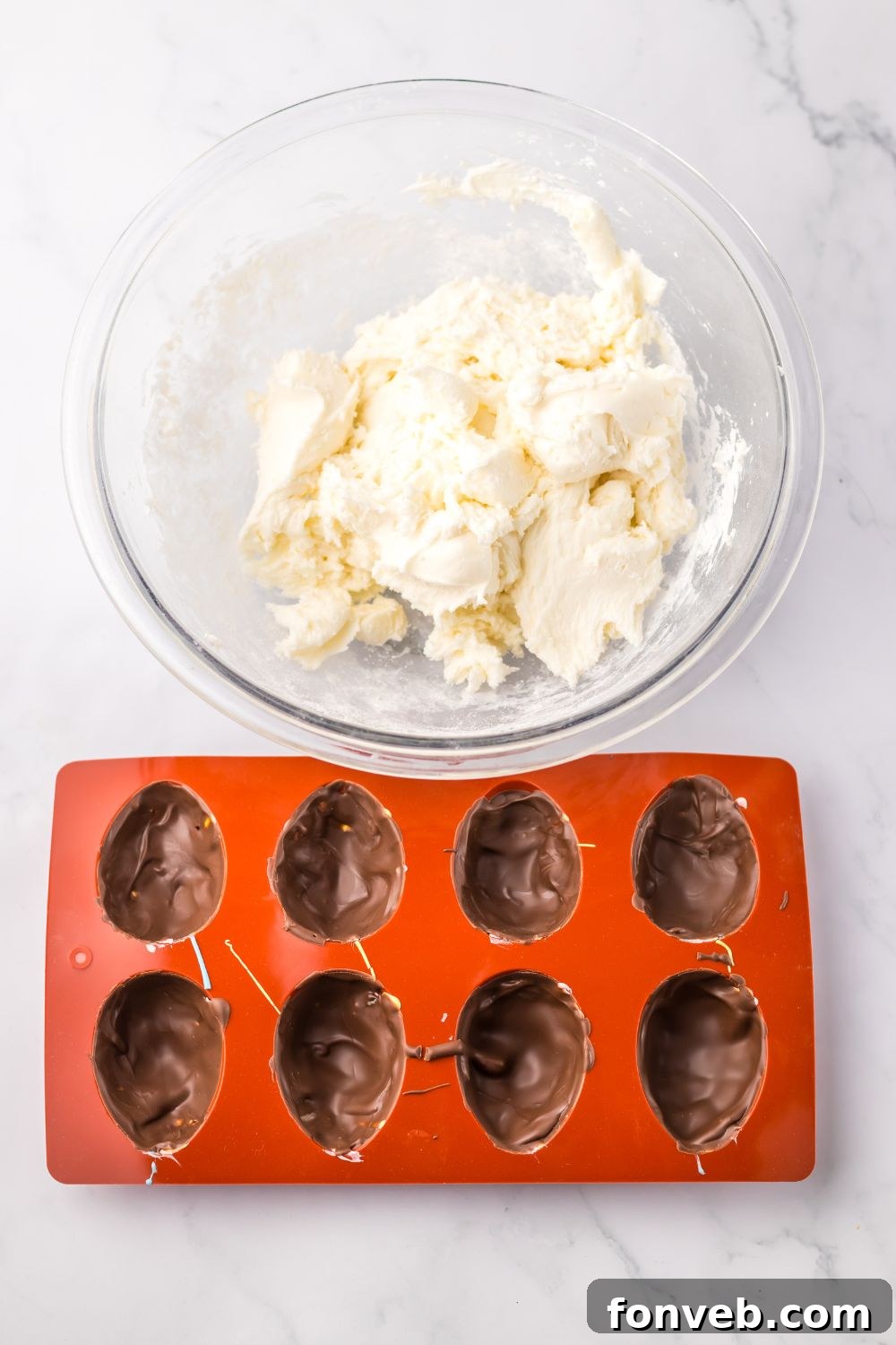 Fluffy Easter Delights 6 chocolate coating in a silicone mold ith marshmallow mixture in bowl by it for making a Easter Marshmallow Eggs