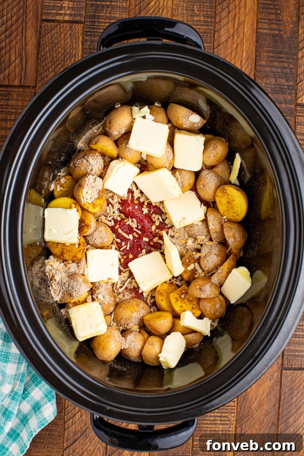 Pats of butter placed on top of the steak and potatoes in the slow cooker