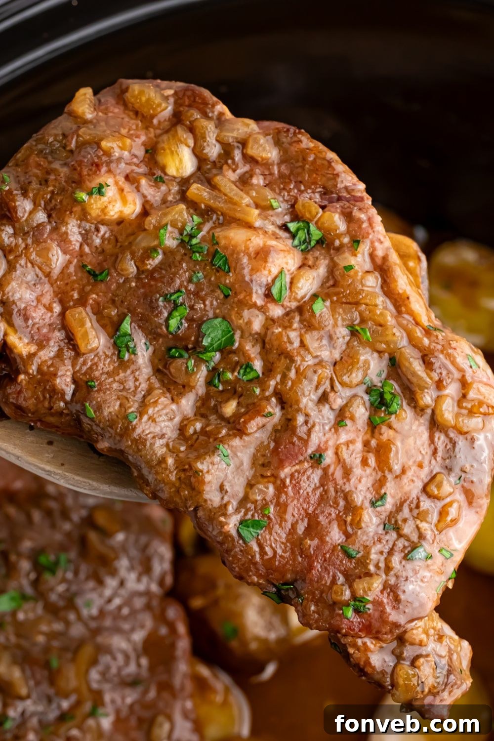 A spoonful of tender steak lifted from the crock pot, demonstrating the cooked Crock Pot Steak and Potatoes