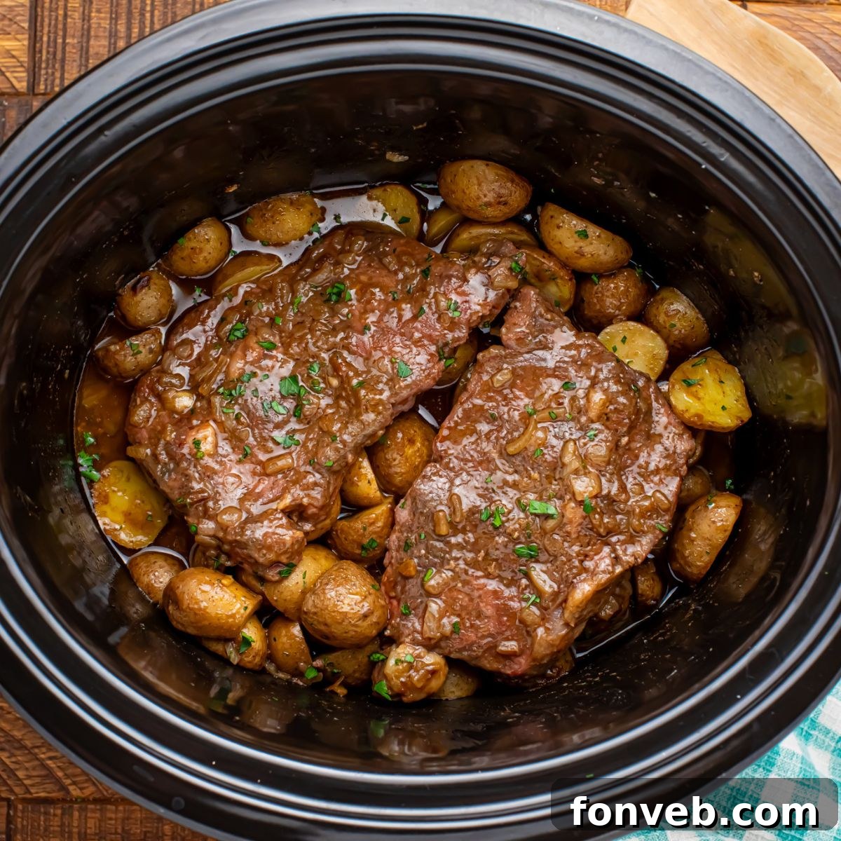 Crock Pot Steak and Potatoes served in a slow cooker on a rustic table setting