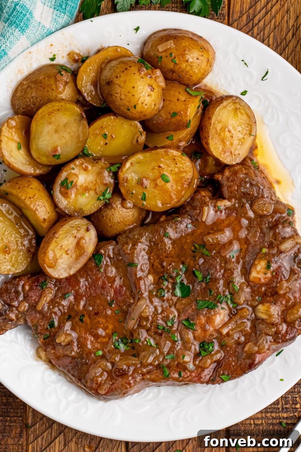 A single piece of tender steak being lifted from a plate of Crock Pot Steak and Potatoes