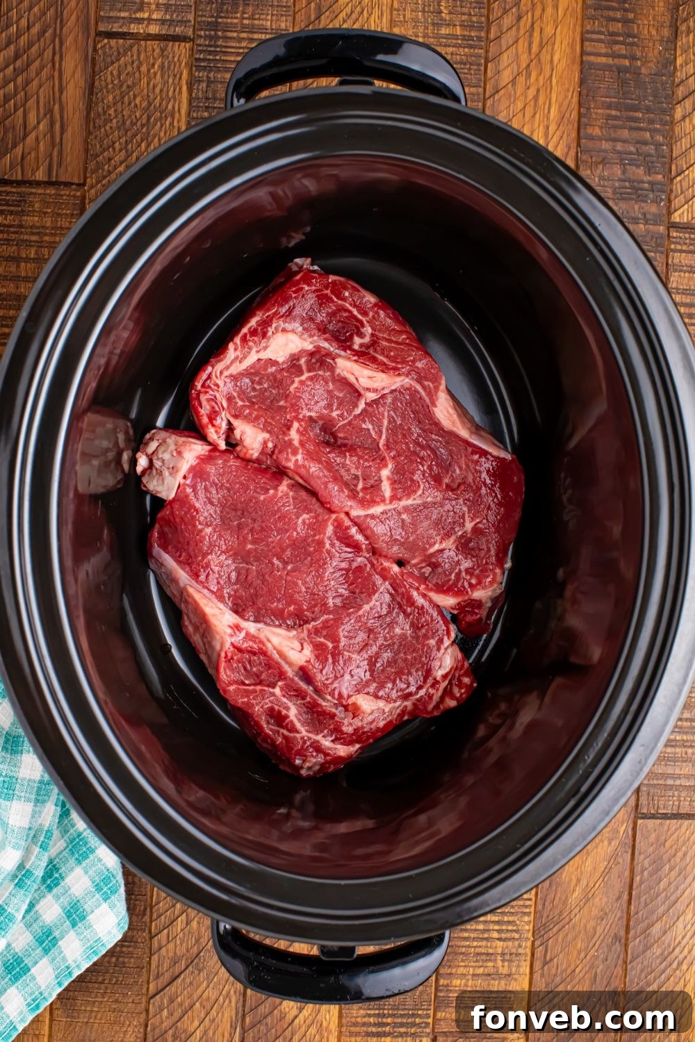 Raw seasoned steak placed in the crock pot, ready for slow cooking