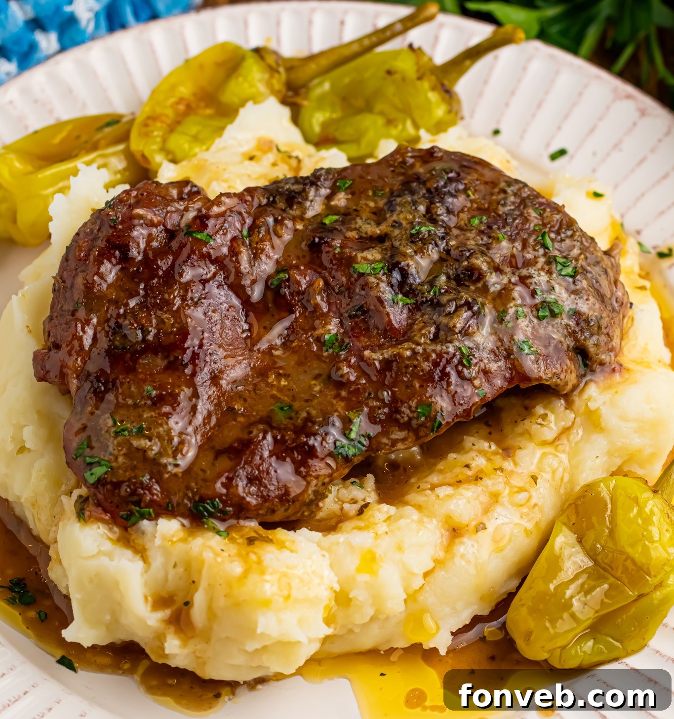Up close shot of the Slow Cooker Mississippi Ribeye Steaks on a white plate, on top of fluffy mashed potatoes with gravy