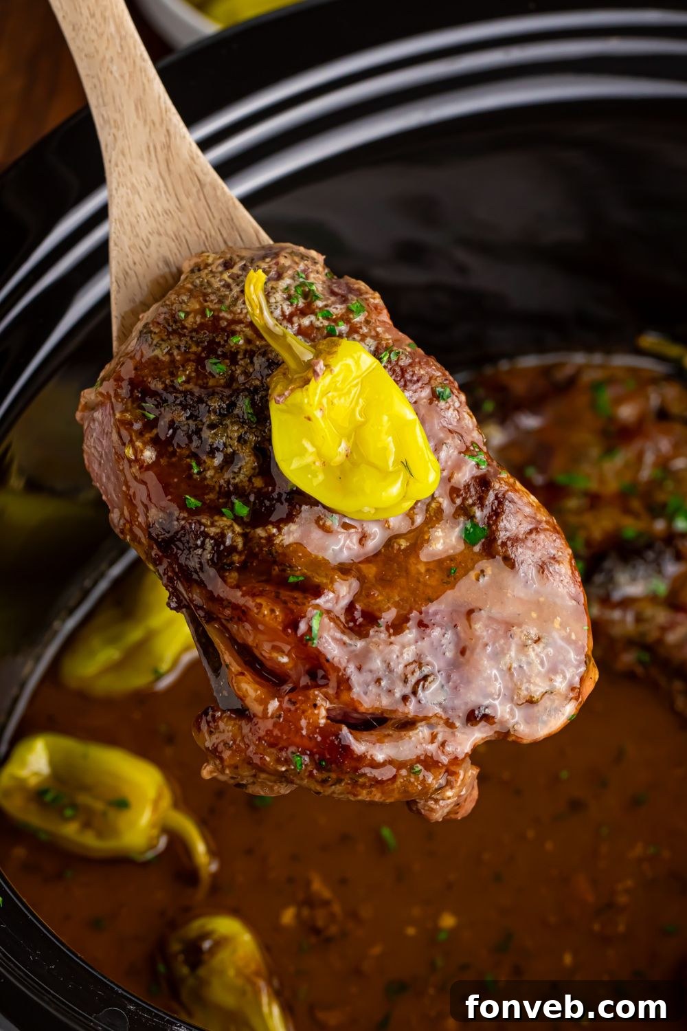 steak being lifted out of slow cooker with spoon - Slow Cooker Mississippi Ribeye Steaks