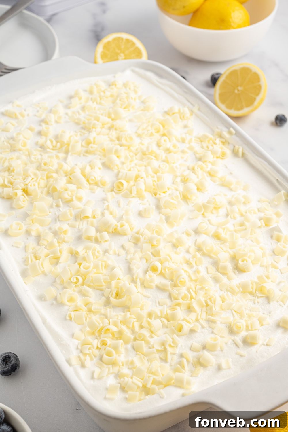 White chocolate shavings sprinkled generously over the top of the finished Lemon Blueberry Lush dessert, sitting on a table.