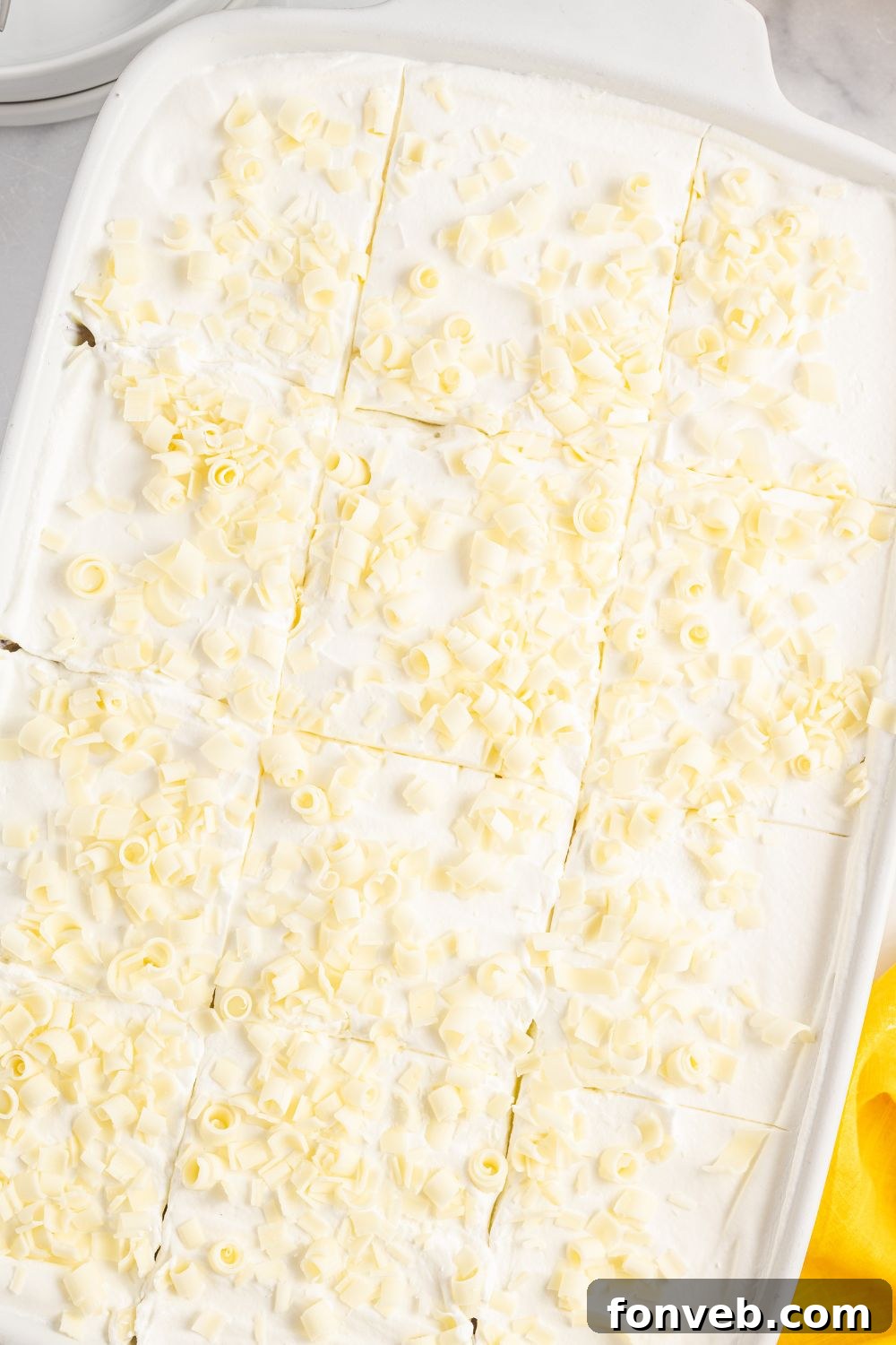 Overhead view of a lemon delight dessert in a casserole pan on a table, showcasing its complete and chilled state.