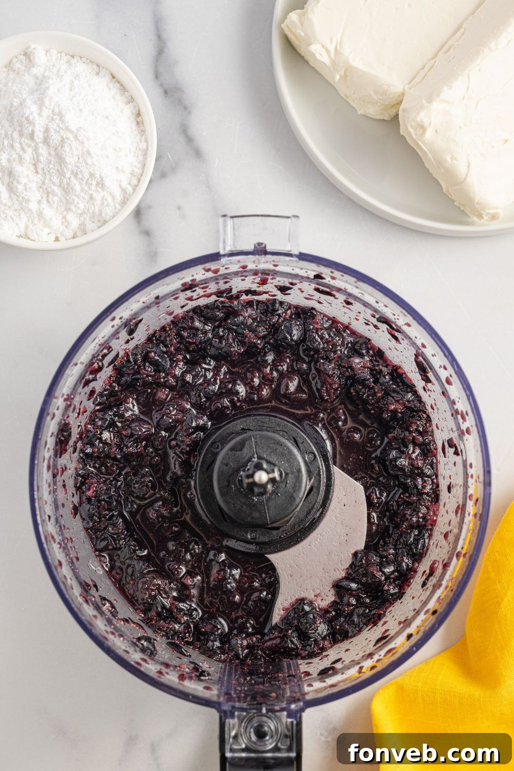 Blueberries in a food processor, partially blended, prepared for the creamy filling of the Lemon Blueberry Lush.