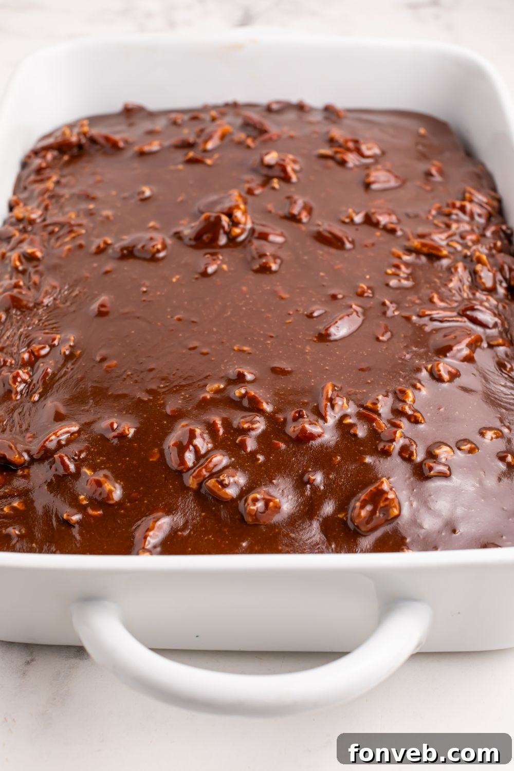 Classic Dr. Pepper Cake 11 A completed Dr. Pepper Cake, glistening with its rich glaze, resting in the baking pan on a wooden table, ready to be sliced.
