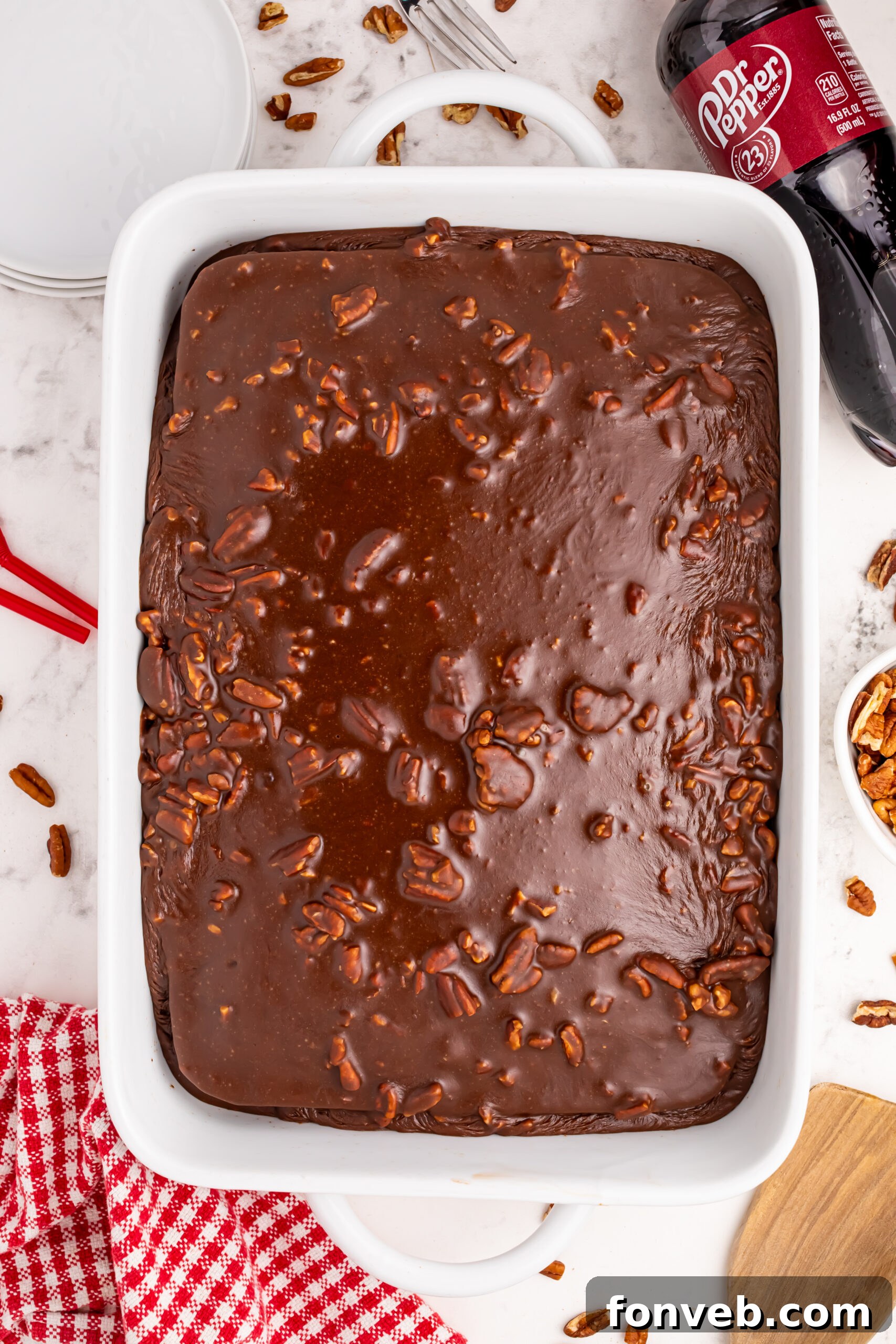 Classic Dr. Pepper Cake 12 A close-up shot of a single slice of Dr. Pepper Cake on a plate, adorned with a swirl of whipped cream and a glistening cherry, ready to be enjoyed.