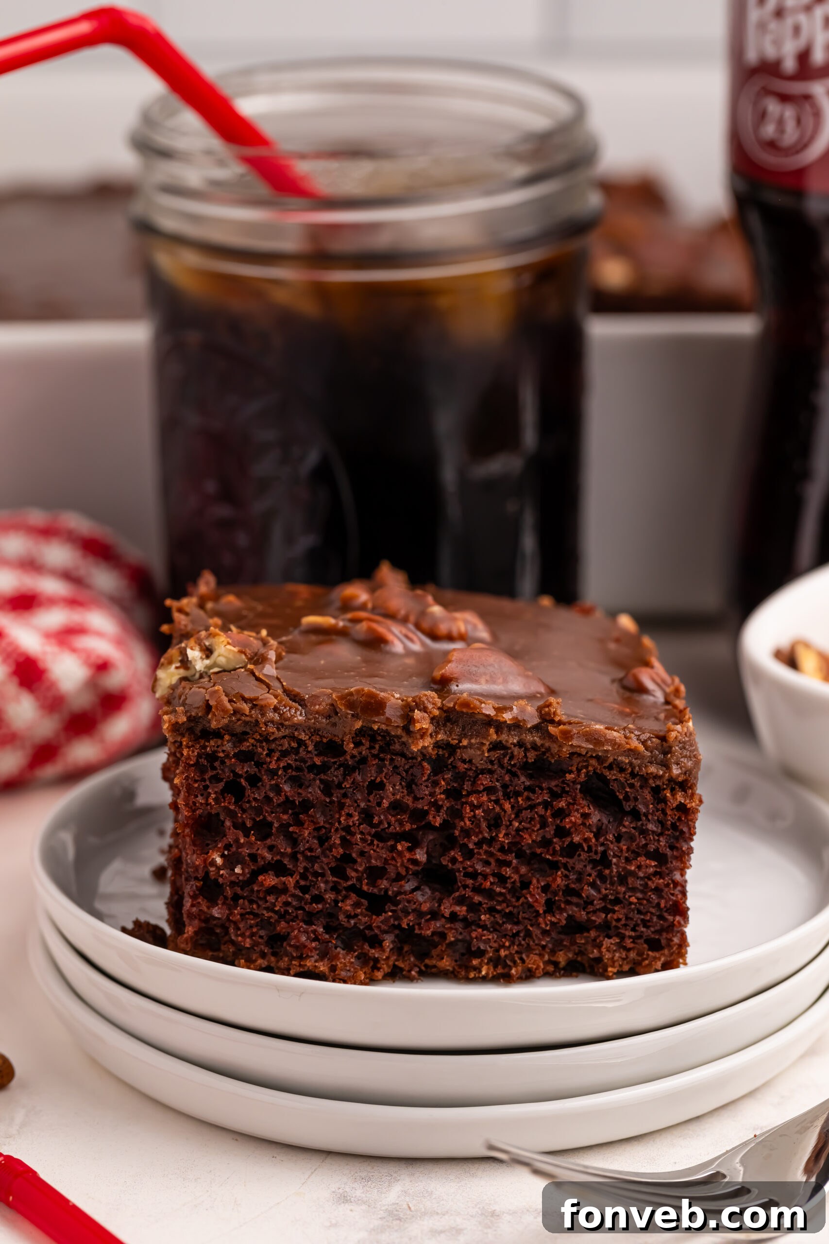 Classic Dr. Pepper Cake 14 A pristine slice of Dr. Pepper Cake on a white plate, positioned in front of a glass filled with Dr. Pepper, emphasizing the soda's role in the dessert.