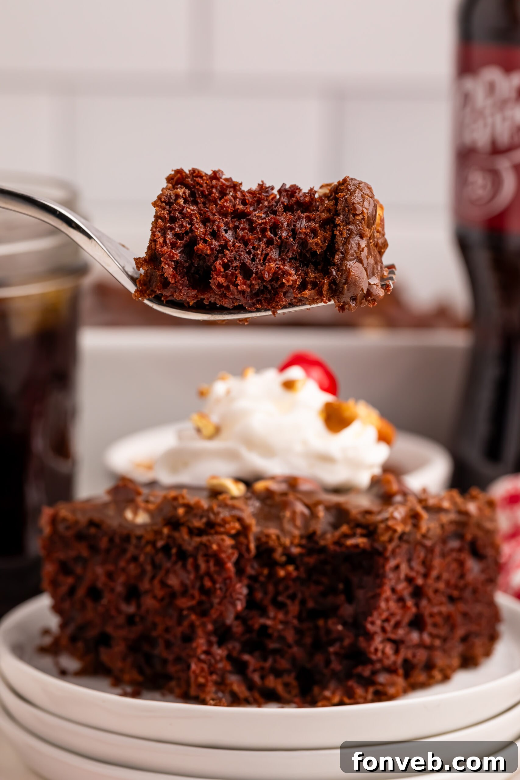 Classic Dr. Pepper Cake 17 A fork holding a bite of Dr. Pepper Cake, poised over a slice on a plate, highlighting the cake's moist interior and the thick glaze.