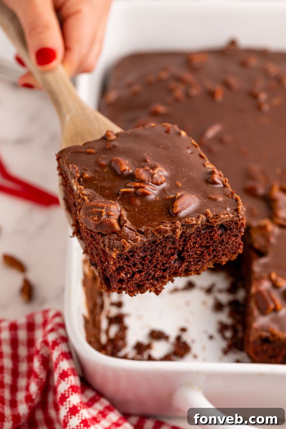 Classic Dr. Pepper Cake 19 A Dr. Pepper Cake in its pan, with a single slice being carefully lifted out by a spatula, showcasing its readiness to be enjoyed.
