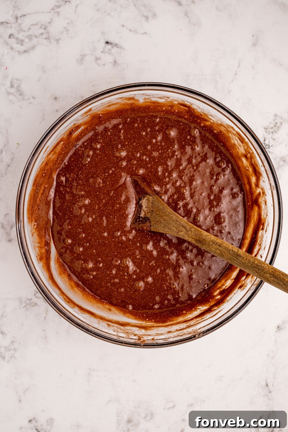 Classic Dr. Pepper Cake 6 Rich chocolate cake batter in a clear glass bowl, showcasing its smooth, consistent texture before baking.