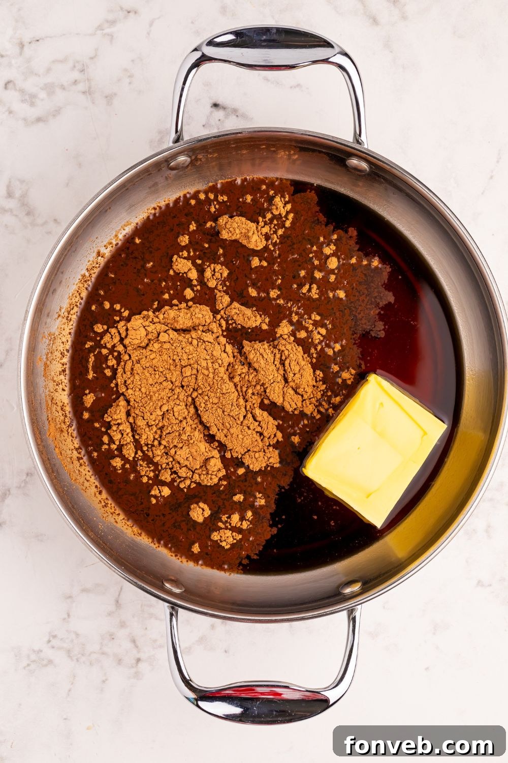 Classic Dr. Pepper Cake 9 Unsweetened cocoa powder and a stick of butter waiting in a small metal saucepan on a wooden table, preparing for the rich Dr. Pepper glaze.