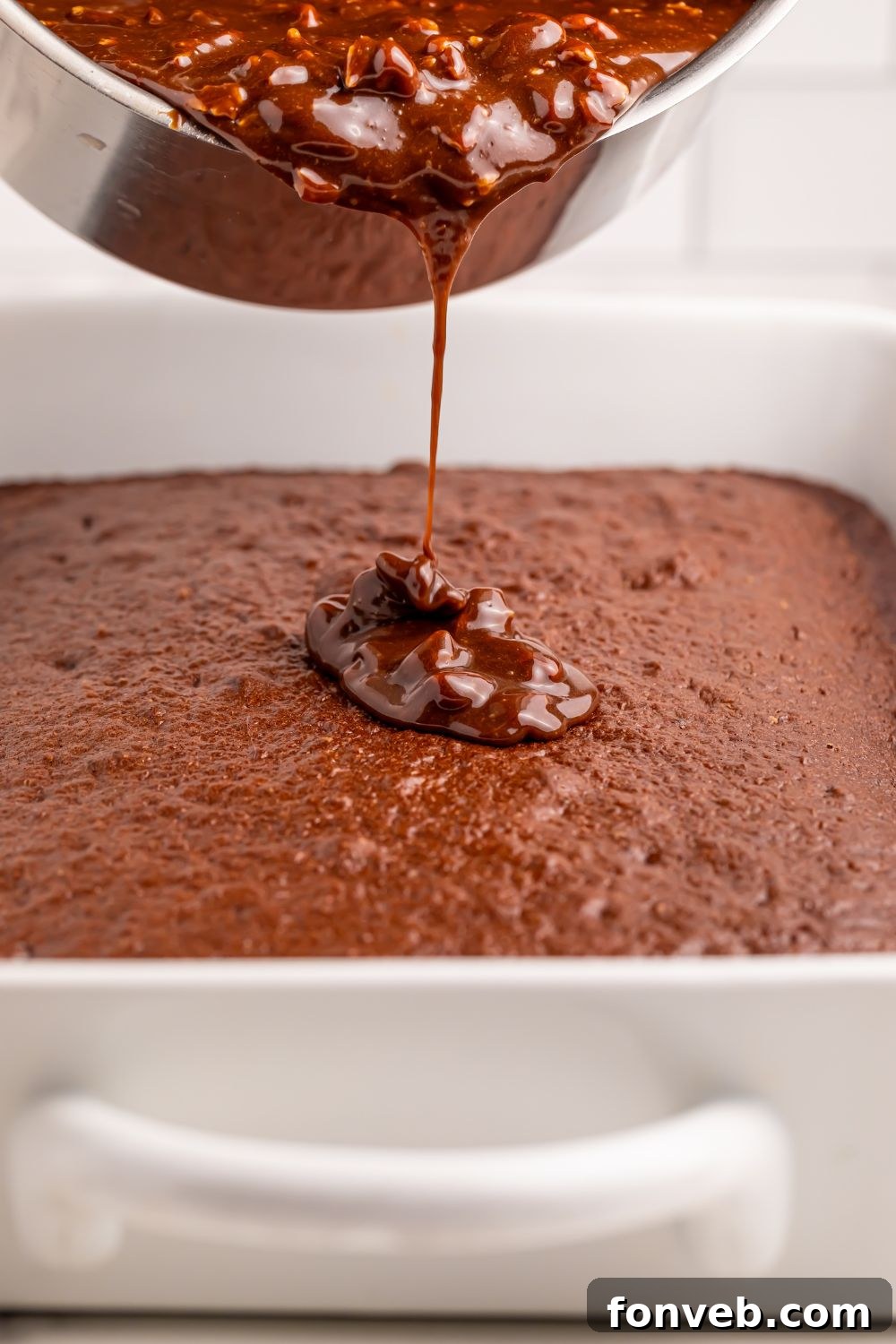 Classic Dr. Pepper Cake 10 A warm, glossy Dr. Pepper glaze being generously poured over the surface of a freshly baked chocolate cake, creating a smooth, even coating.