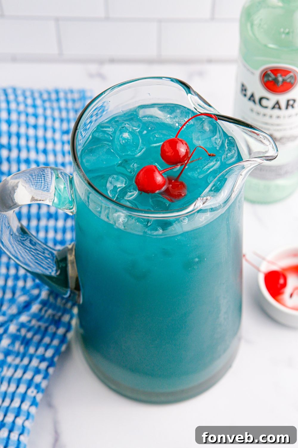 A pitcher of Blue Hawaiian Punch on a table, draped with a blue checkered towel, emphasizing its chilled and ready-to-serve state.