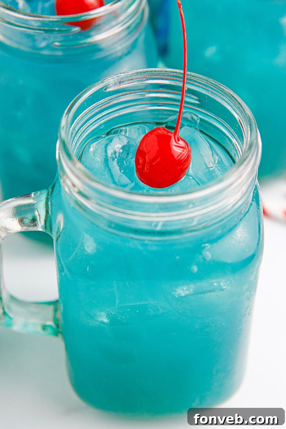Several hurricane glasses filled with blue cocktails, adorned with garnishes, sitting invitingly on a table.