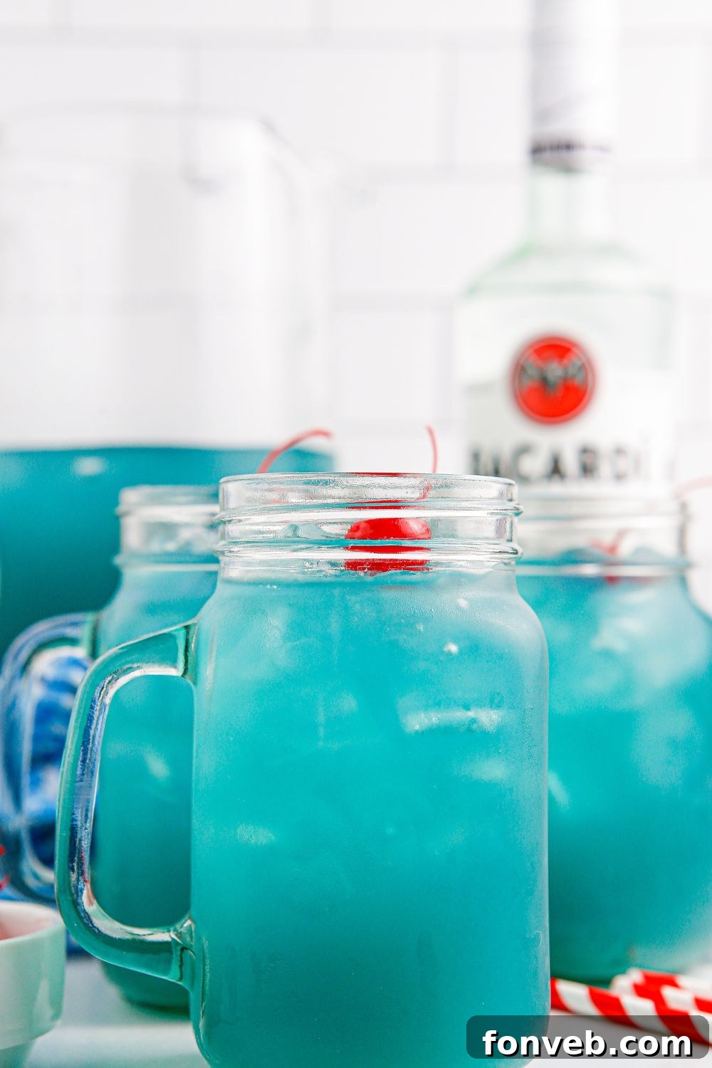 Glasses and a pitcher of Blue Hawaiian Punch displayed together on a table, ready for a gathering.