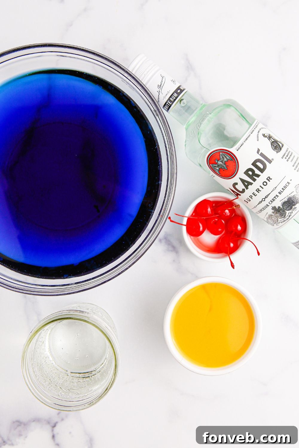 All the essential ingredients for making Hawaiian Punch laid out neatly on a marble counter, ready for mixing.