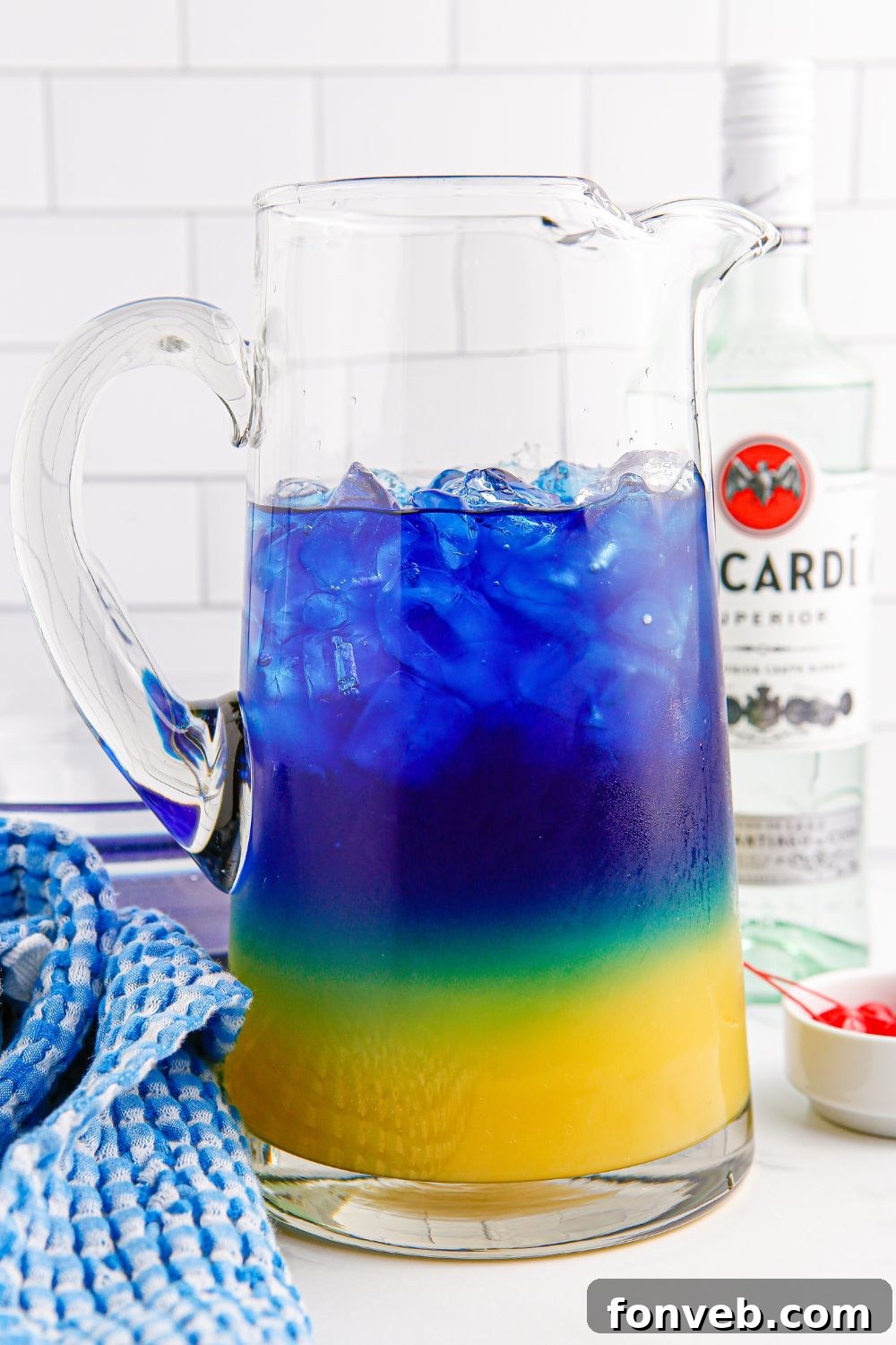 A beautifully layered glass pitcher filled with the Blue Hawaiian Punch, ready to be stirred and served.