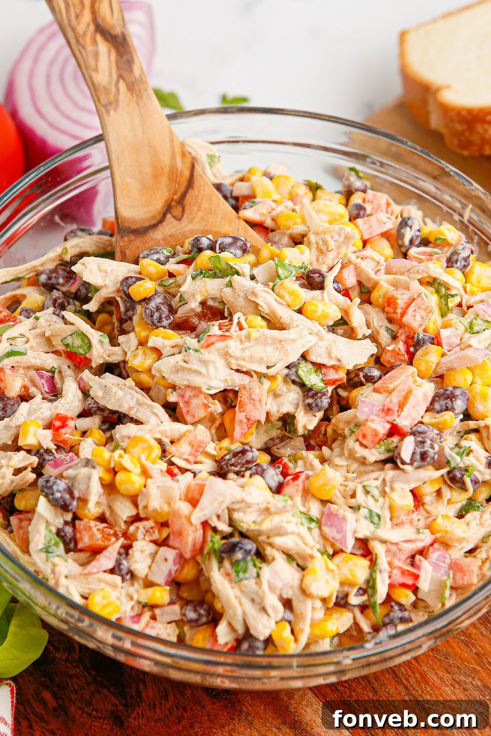 Southwestern Chicken Salad 13 A close-up side view of Southwest Chicken Salad in a bowl, with a wooden spoon partially visible, emphasizing the textures and layers of the salad.