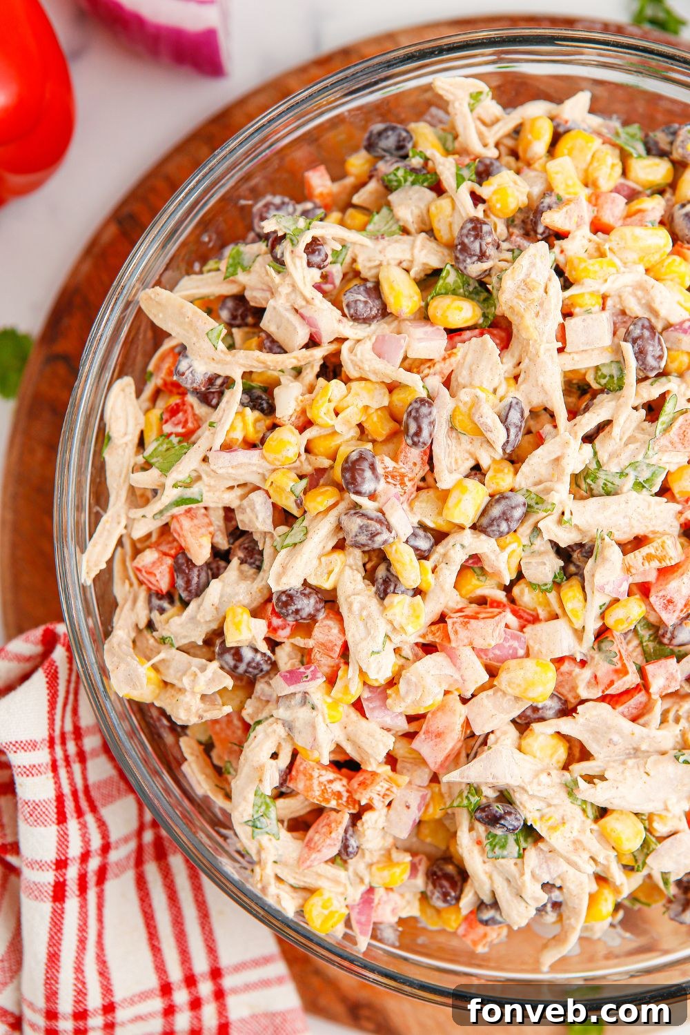 Southwestern Chicken Salad 15 Southwest Chicken Salad presented in a bowl, with fresh tomatoes and a red striped towel as accents, set on a wooden table, emphasizing its freshness and inviting presentation.