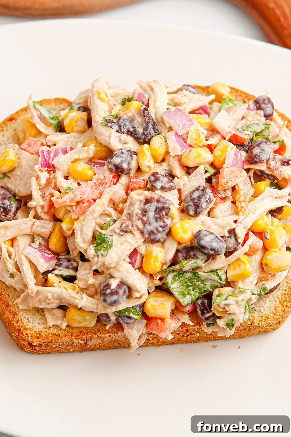Southwestern Chicken Salad 3 A serving of Southwest Chicken Salad artfully placed on a slice of golden-brown bread, presented on a white plate, ready to be enjoyed as a sandwich.