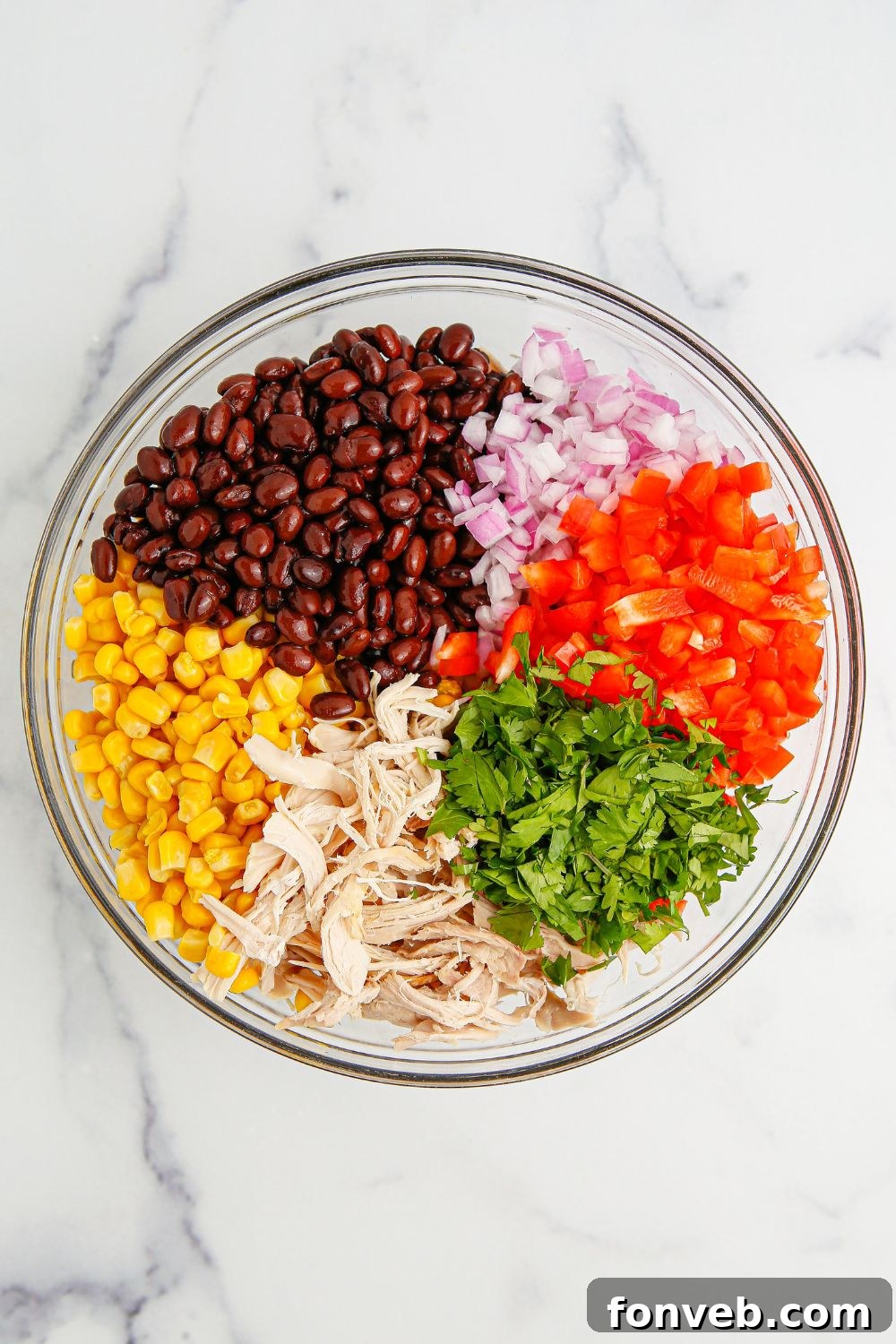 Southwestern Chicken Salad 6 Freshly chopped ingredients for the Southwest Chicken Salad neatly arranged in a clear glass bowl, showcasing the vibrant colors of bell peppers, corn, and red onions.