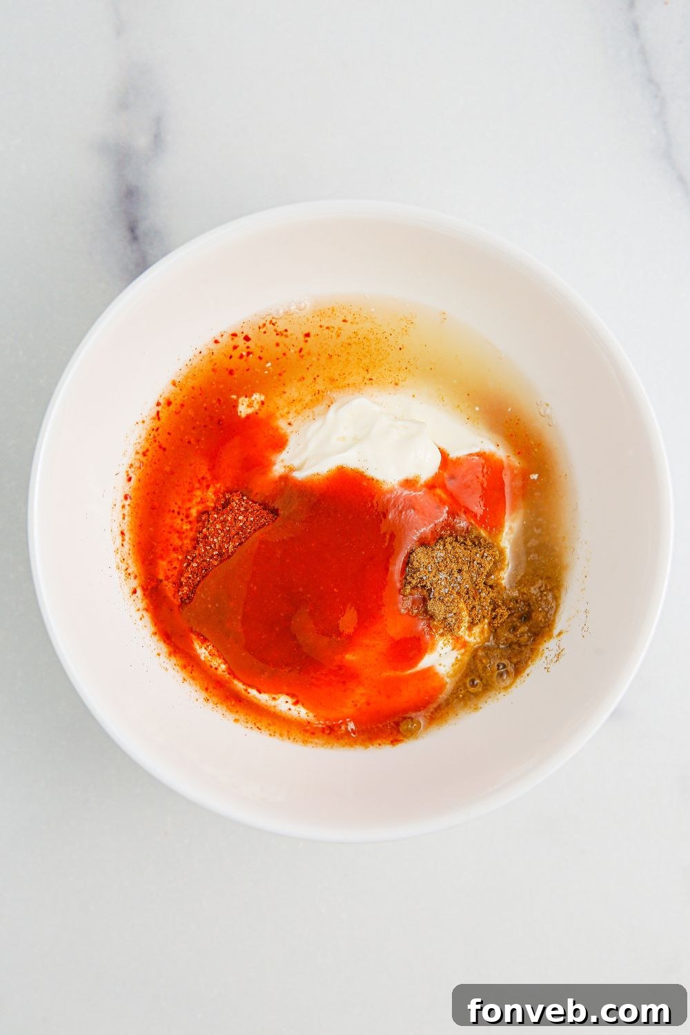 Southwestern Chicken Salad 8 Separate bowls displaying the individual components for the Southwest Chicken Salad dressing, including sour cream, lime, and spices, set on a clean white table, ready for whisking.
