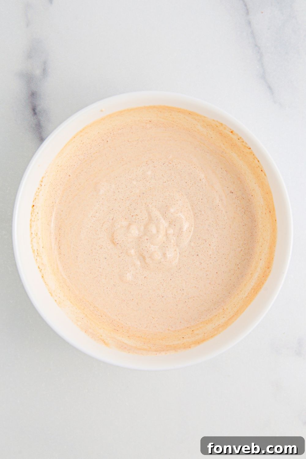 Southwestern Chicken Salad 9 A smooth, creamy sour cream dressing, perfectly whisked and ready, presented in a small white bowl on a simple table surface, awaiting its addition to the salad.