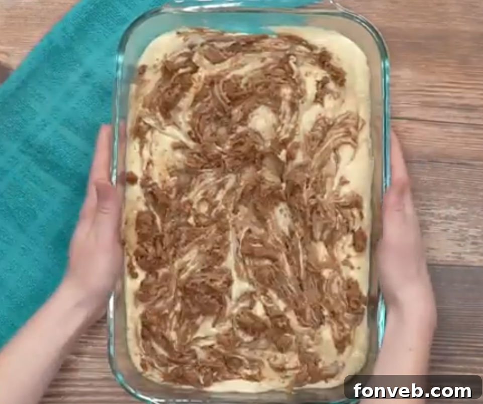 Irresistible Cinnamon Roll Cake 4 A warm, freshly baked cinnamon roll cake being removed from the oven, its golden-brown crust and sweet aroma filling the kitchen.