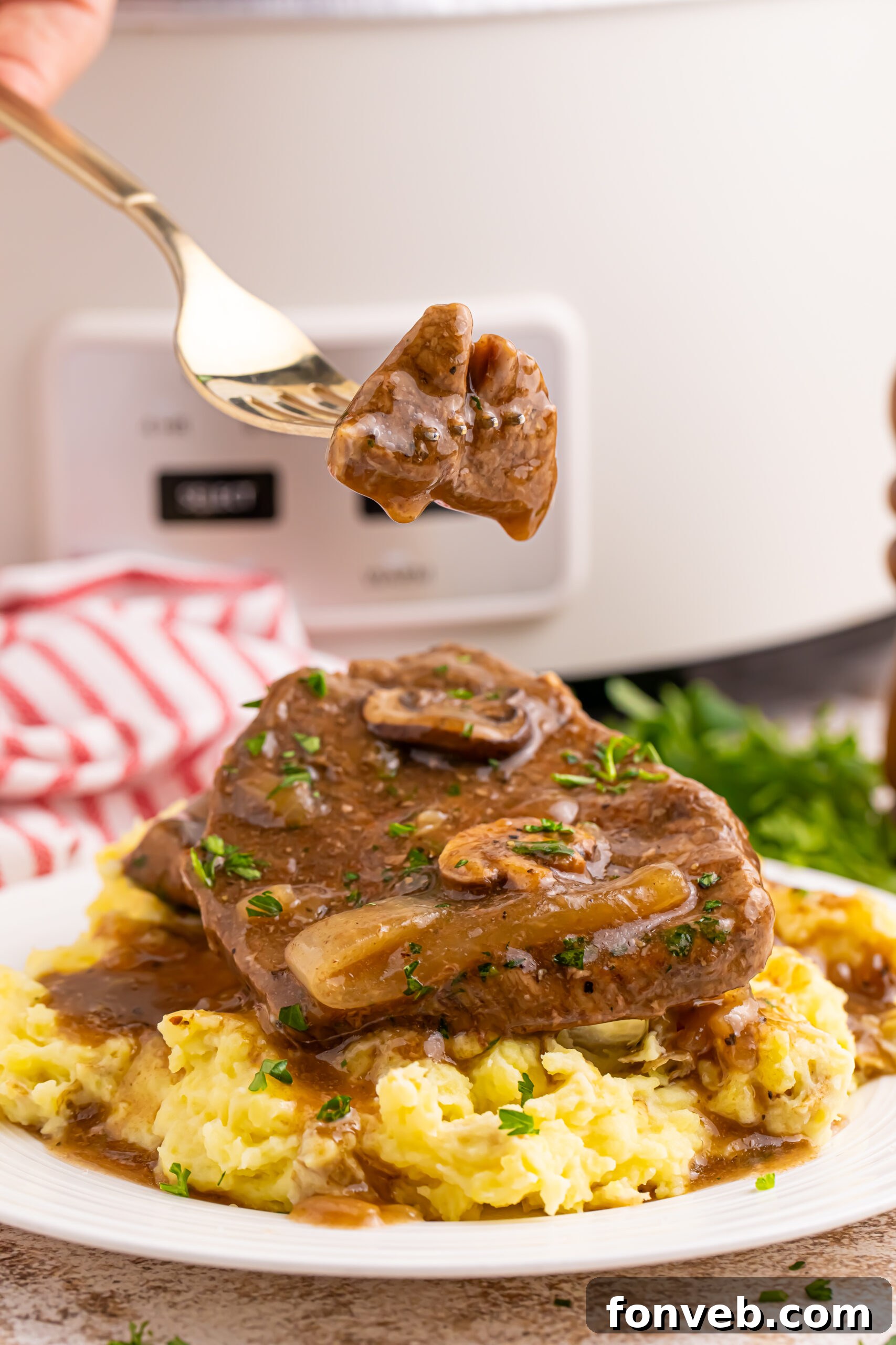 steak, gravy, and potatoes on a plate with a fork with a bit of the Slow Cooker Round Steak and Gravy on it