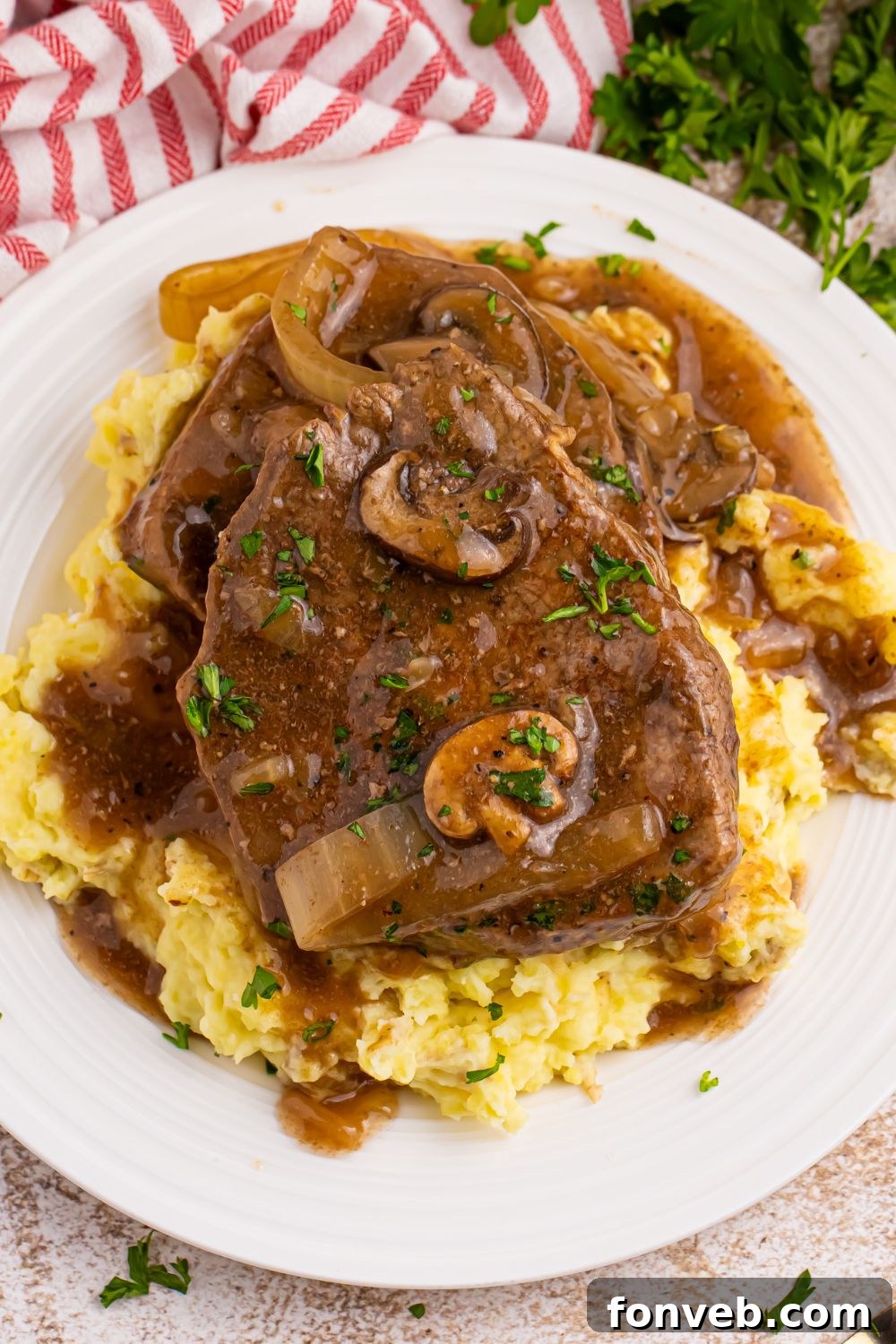 steak on top of mashed potatoes smothered in gravy from the Slow Cooker Round Steak and Gravy recipe 