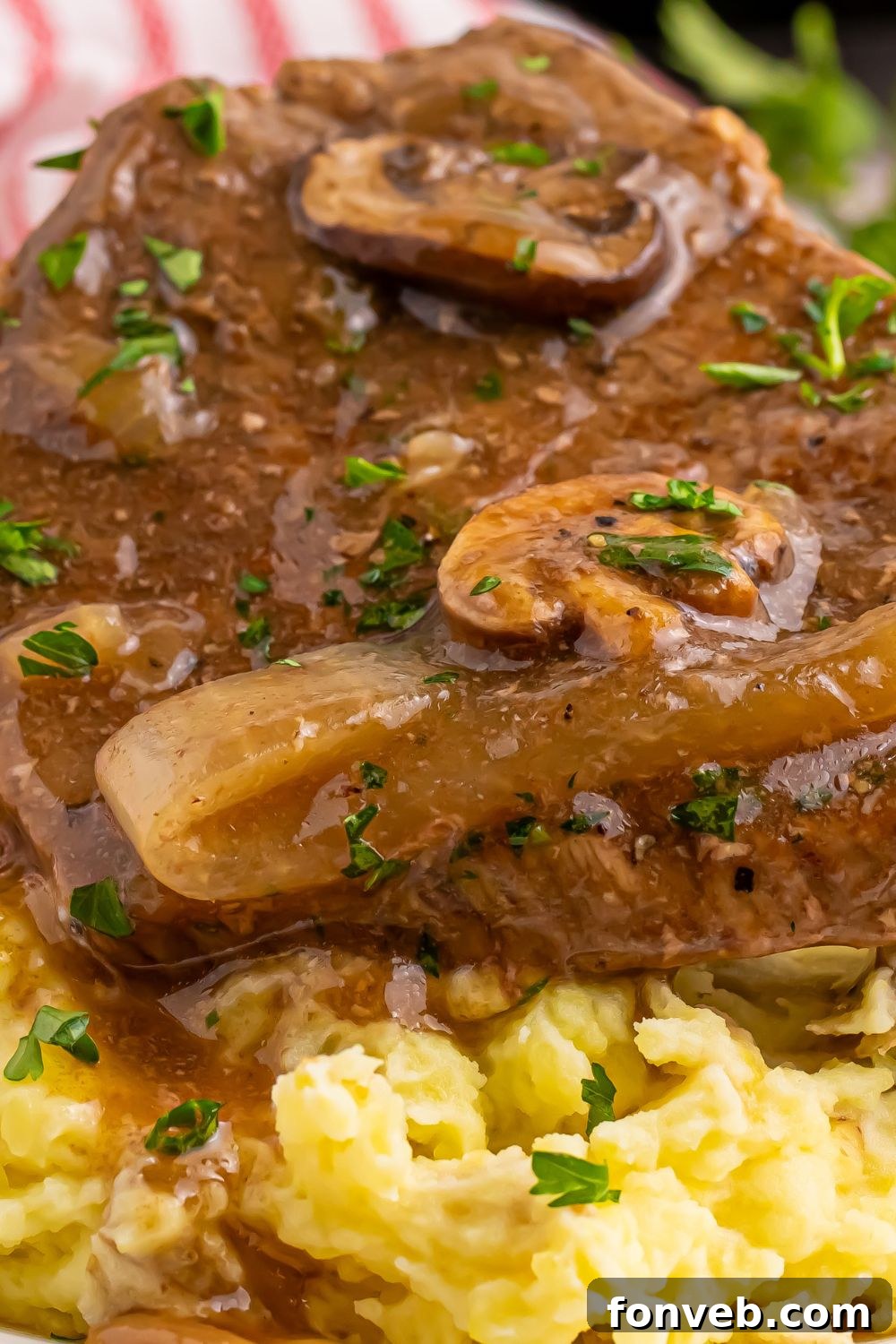 Round Steak and Gravy  on a plate with a close up to se the mushrooms and onions in the thick brown gravy on top of steak 