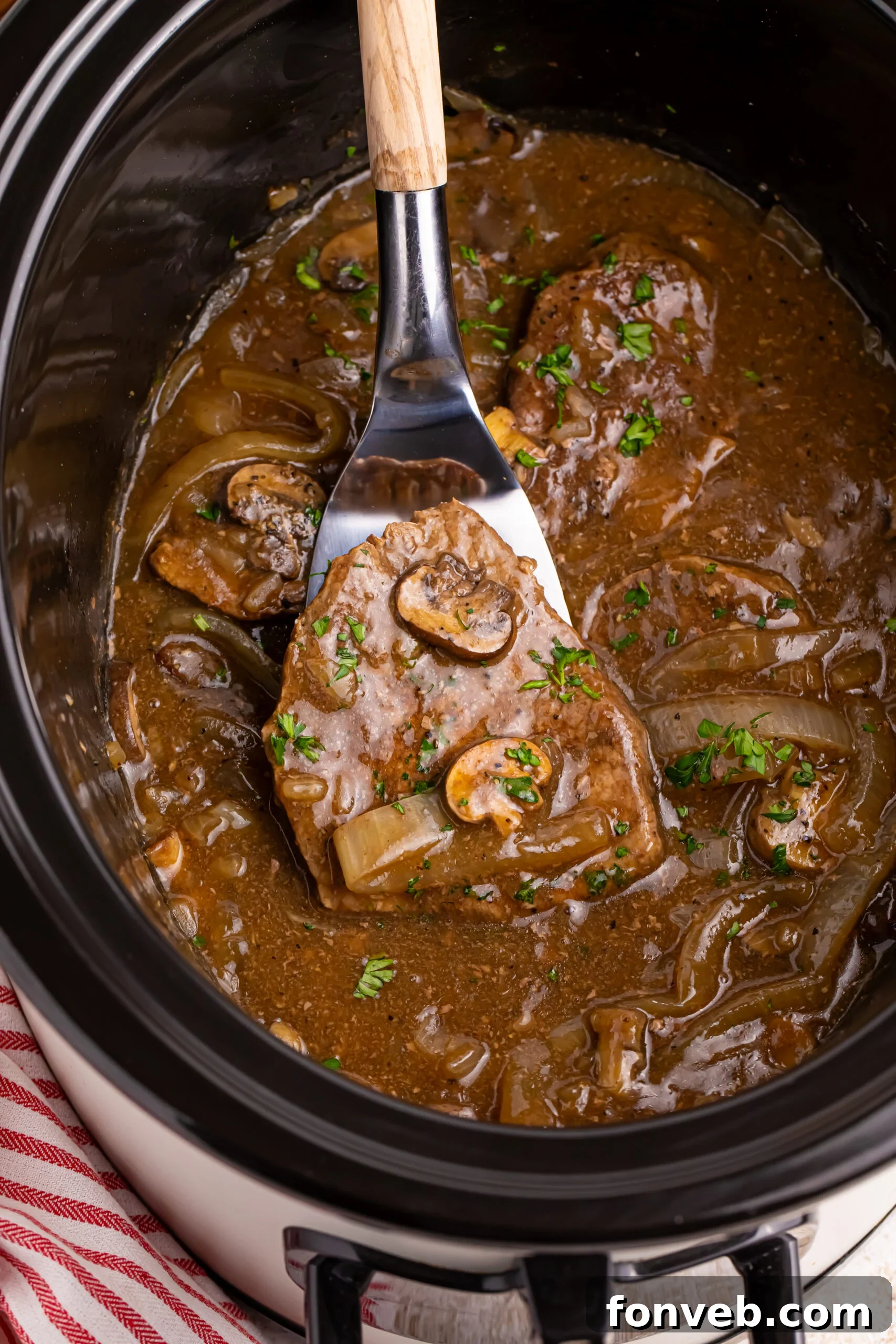 Crock pot filled with steak, onions and mushroom gravy