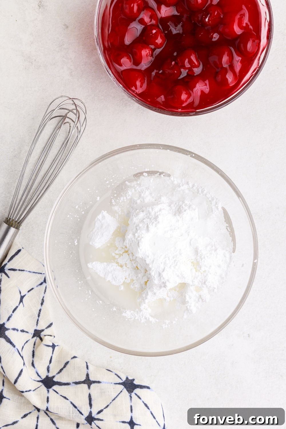 powdered sugar glaze ingredients in a glass bowl with a whisk by it and bowl of pie filling