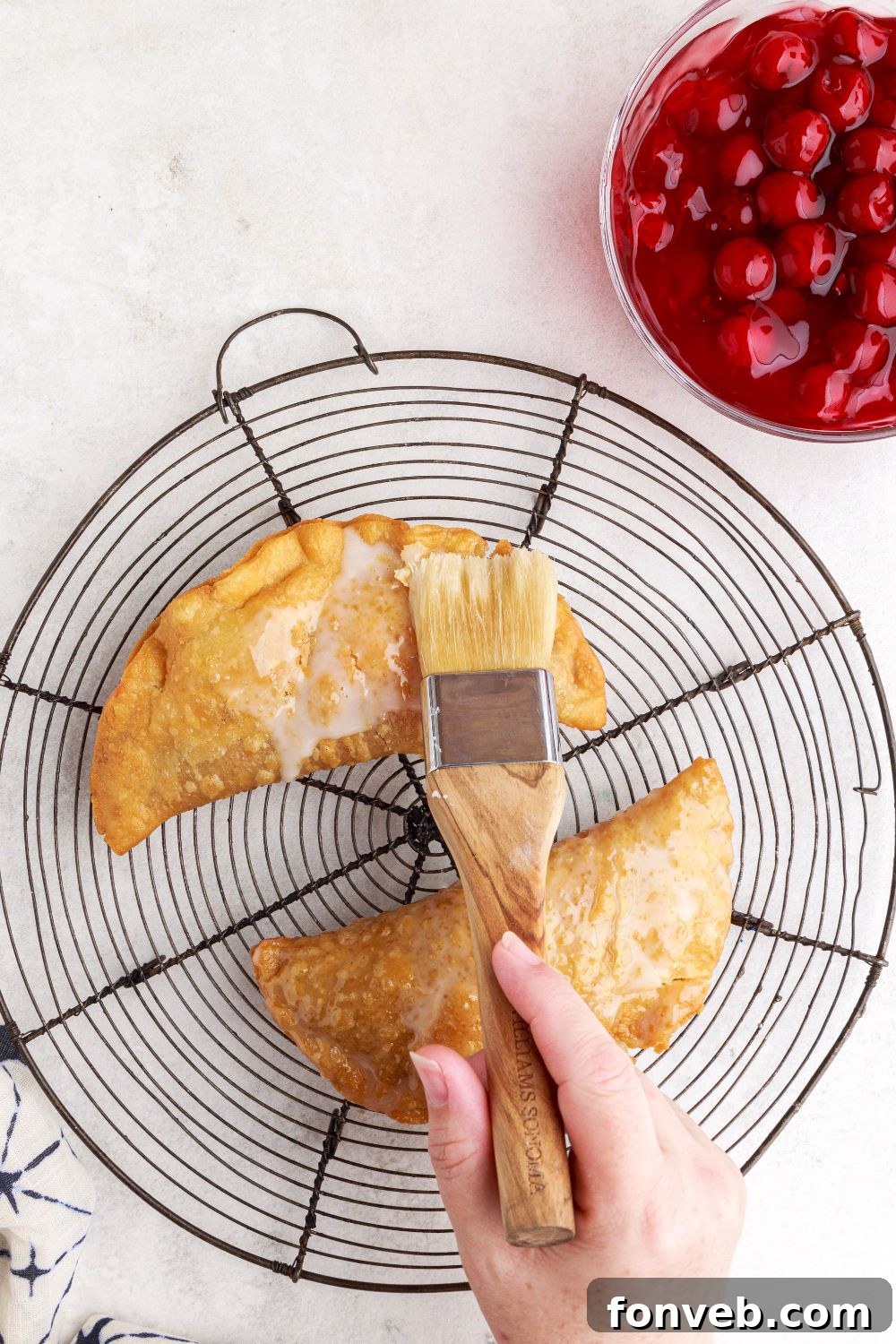 brushing glaze onto the cooked Cherry Cheesecake Hand Pies