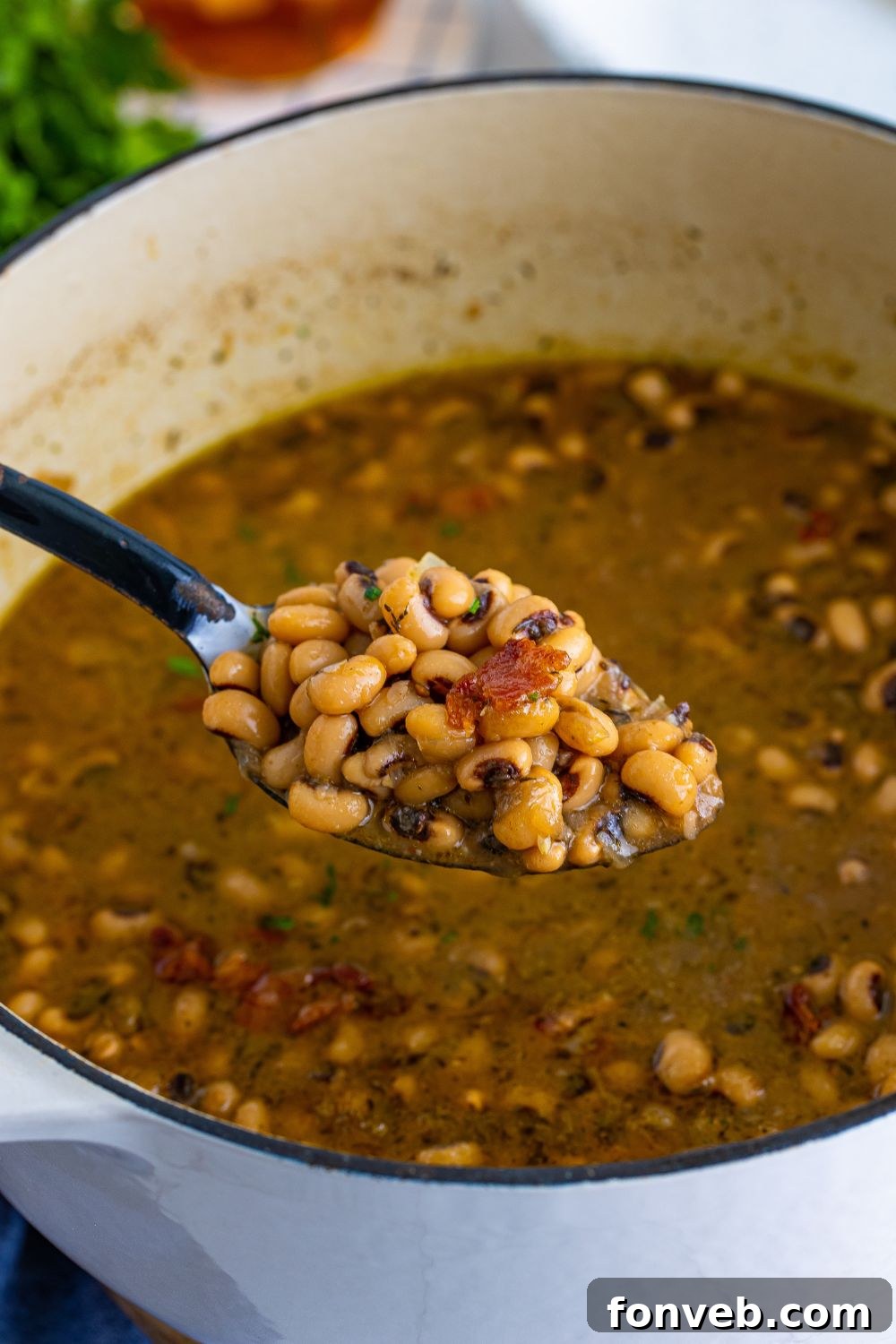 Dutch oven with a spoonful of black eyed peas and a pot of black eyed peas