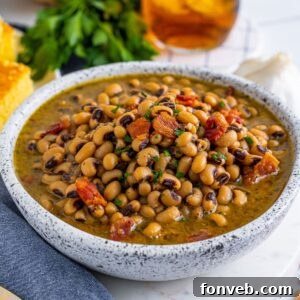 Black Eyed Peas in a bowl with fresh herbs and a drink sitting behind the bowl on the table