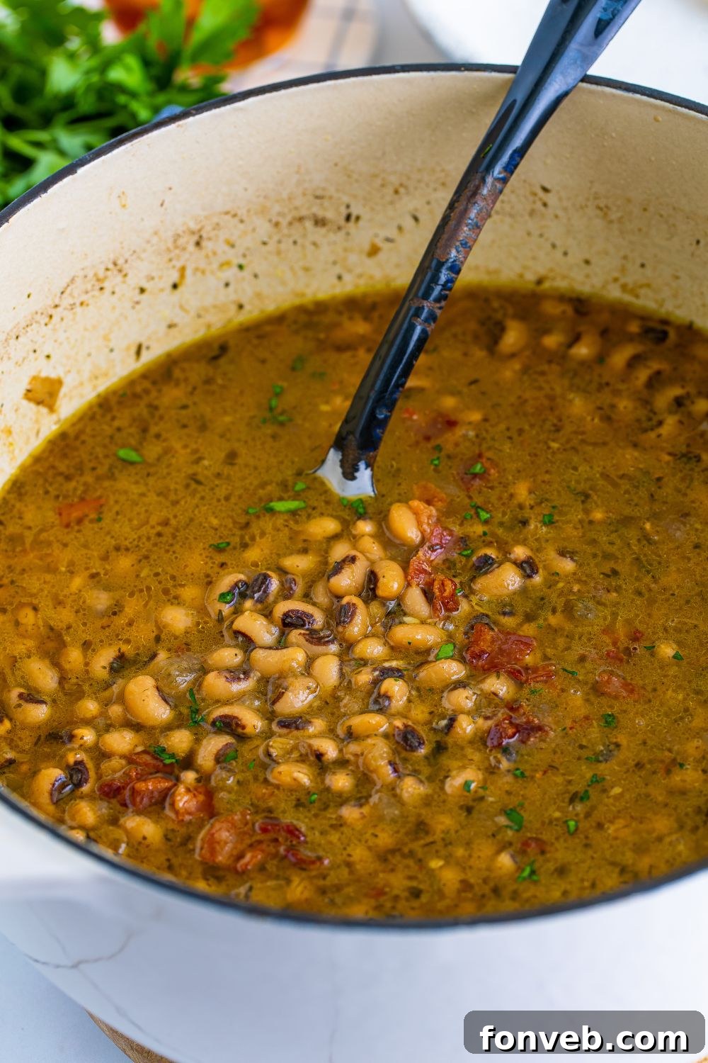 black eyed peas in a pot with a metal spoon showing the peas 