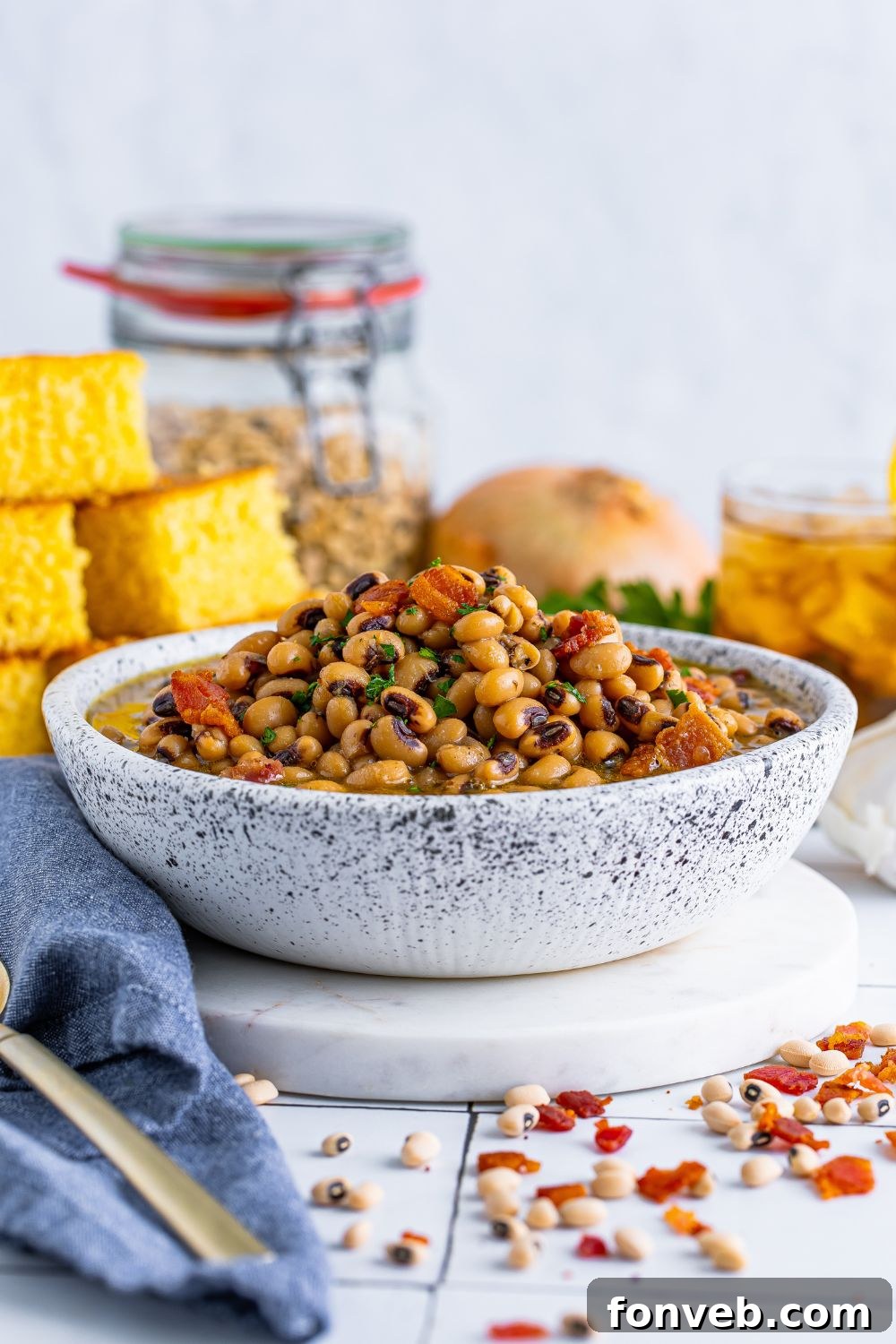 Black Eyed Peas in a small bowl with cornbread, onion, tea and more sitting around the bowl on the table