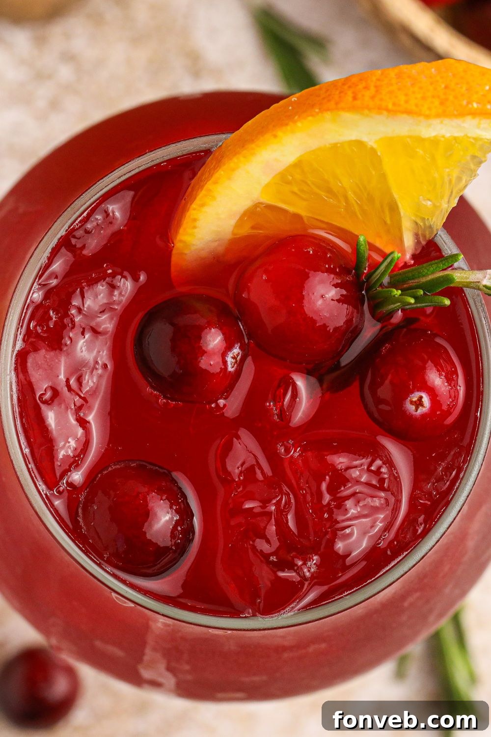 Crimson Whiskey Zing 7 overhead look of cranberry cocktail in a glass with fresh cranberries and an orange slice in glass