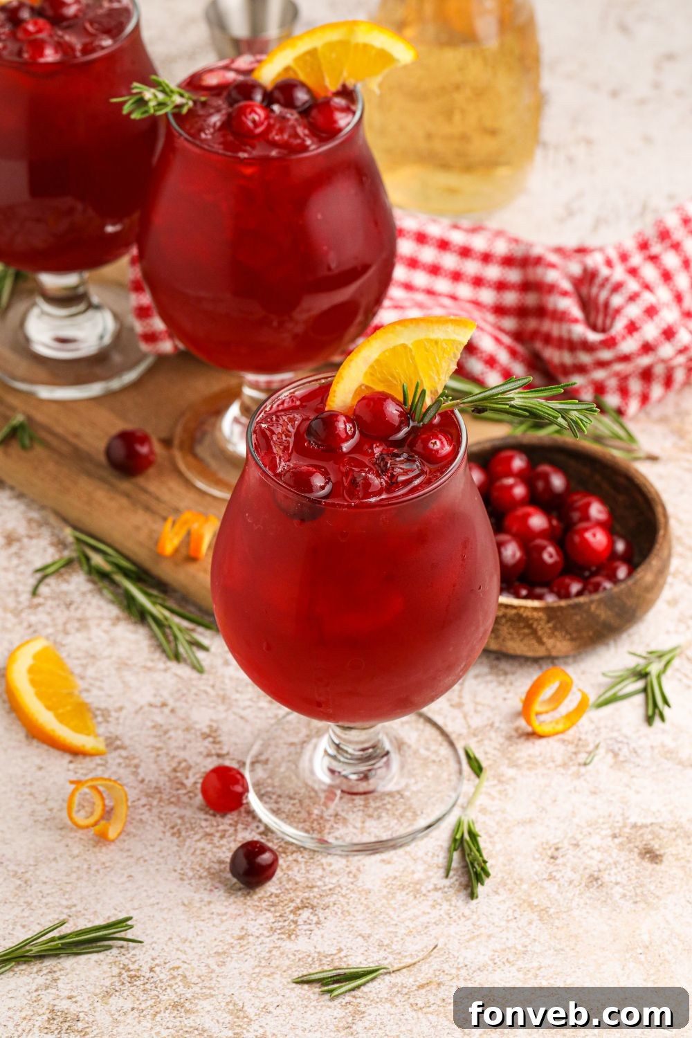 Crimson Whiskey Zing 9 cocktail glasses filled with a cranberry whiskey sour and sliced oranges and cranberries scatterd on table