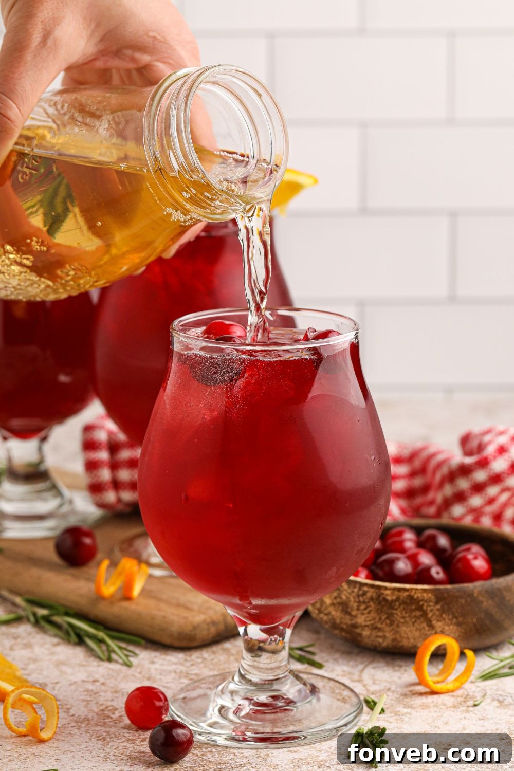 Crimson Whiskey Zing 10 Cranberry Whiskey Sour on table with some juice being poured in the glass to top it off