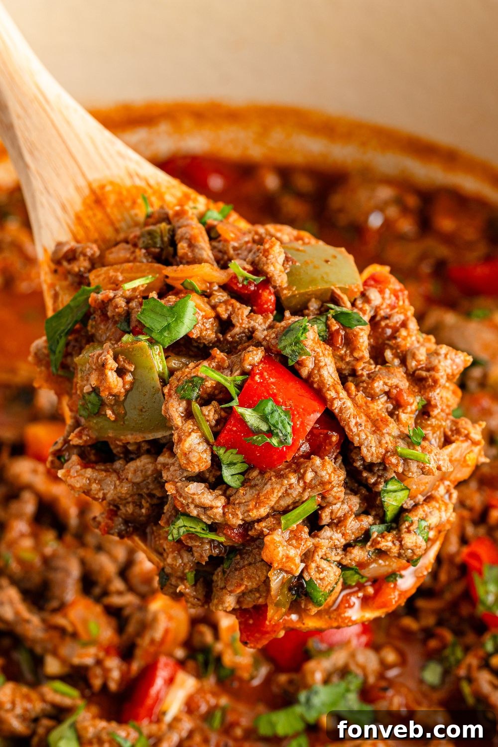 Zesty Ground Beef Medley 14 A wooden spoon lifting a portion of Carne Picada from a Dutch oven, highlighting the rich, thick sauce and tender beef