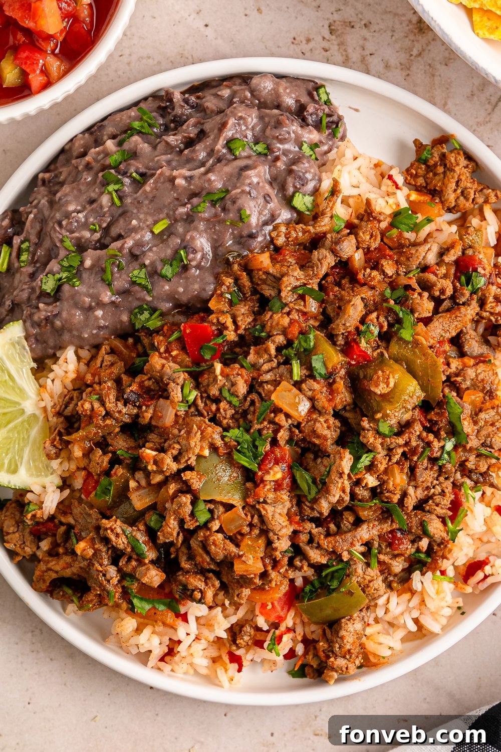 Zesty Ground Beef Medley 10 A plate featuring a complete Carne Picada meal with rice, black beans, and other accompaniments, ready to be served