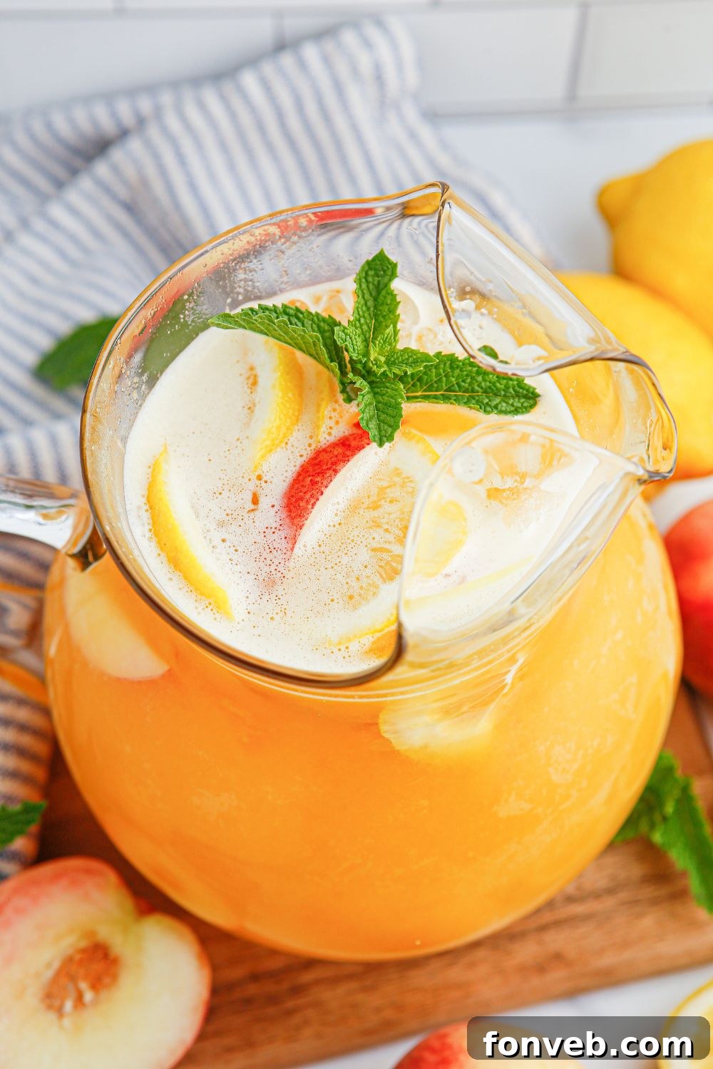 Sun-Kissed Peach Lemonade 12 Peach Lemonade in a pitcher with a garnish on mint