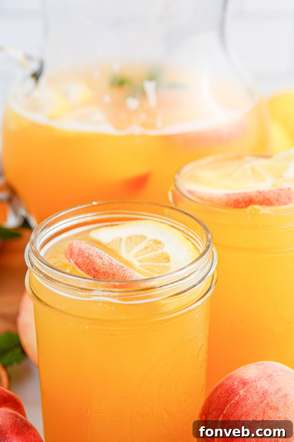 Sun-Kissed Peach Lemonade 17 Peach Lemonade with sliced peaches and lemons in a glass