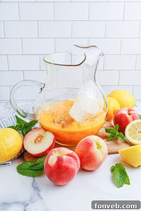 Sun-Kissed Peach Lemonade 8 peach concentrate in a large picture with ice and fresh peaches and lemons around it